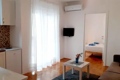 a living room with a table and a room with a bed at Smeštaj Voli - Apartman u centru Sokobanje in Soko Banja