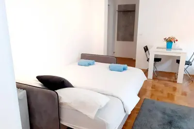 a living room with two white beds and a table at Smeštaj Voli - Apartman u centru Sokobanje in Soko Banja