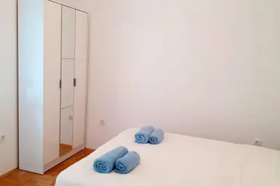 a bedroom with a white bed with blue pillows on it at Smeštaj Voli - Apartman u centru Sokobanje in Soko Banja