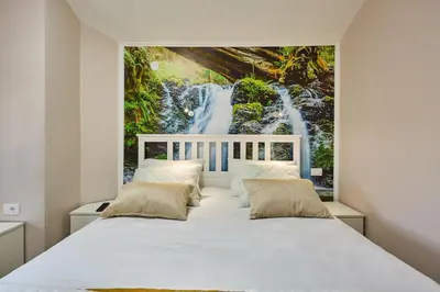 a bedroom with a white bed with a waterfall mural at AquaLux 2 in Soko Banja