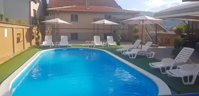 a swimming pool with chairs and umbrellas next to a house at AquaLux 2 in Soko Banja