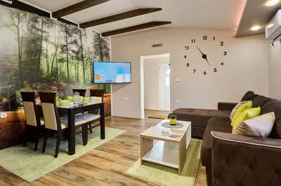 a living room with a table and a clock on the wall at AquaLux 2 in Soko Banja