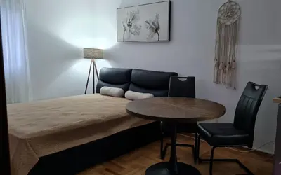 a bedroom with a bed with a table and a couch at Apartman TIM LUX 1 in Vrnjačka Banja