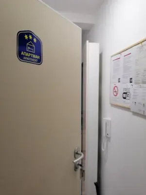 a bathroom with a door with a sign on the wall at Ramonda Lux apartman in Vrnjačka Banja
