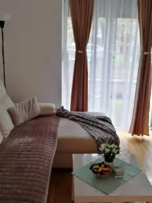 a bedroom with a bed with a table and a window at Ramonda Lux apartman in Vrnjačka Banja