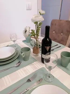 a table with a bottle of wine and glasses on it at Ramonda Lux apartman in Vrnjačka Banja