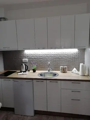 a kitchen with a sink and white cabinets at Ramonda Lux apartman in Vrnjačka Banja