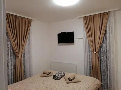 a bedroom with a bed with curtains and a flat screen tv at Ramonda Lux apartman in Vrnjačka Banja