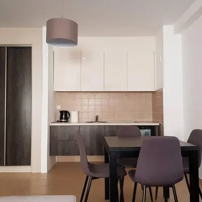 a kitchen with a table and chairs and a kitchen with white cabinets at Apartman Ibarstar in Vrnjačka Banja