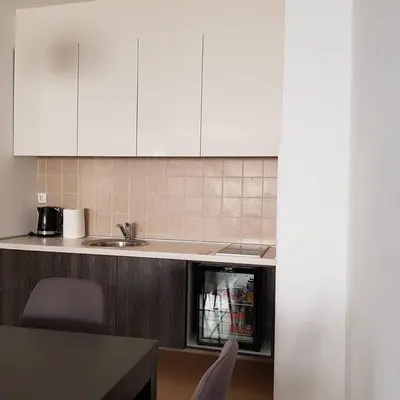 a kitchen with white cabinets and a table and chairs at Apartman Ibarstar in Vrnjačka Banja