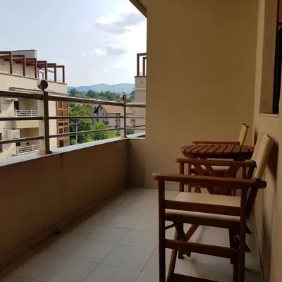 a balcony with two chairs and a table and a window at Apartman Ibarstar in Vrnjačka Banja