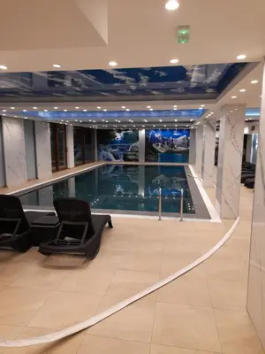 a large swimming pool in a building with chairs at President Kop - Apartman A21 in Kopaonik