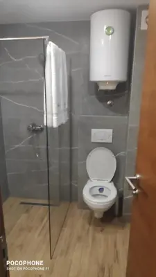 a bathroom with a toilet and a glass shower stall at President Kop - Apartman A21 in Kopaonik