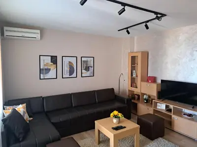 a living room with a black couch and a tv at Apartman Marger in Niš