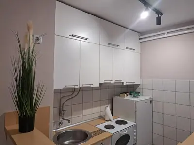 a kitchen with white cabinets and a sink and a refrigerator at Apartman Marger in Niš