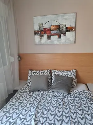 a bedroom with a bed and a painting on the wall at Apartman Marger in Niš