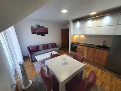 a living room with a couch and a table and chairs at Nina Apartman in Soko Banja