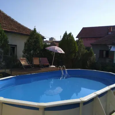 a large blue pool with an umbrella and chairs at Hostel Golub in Zaječar