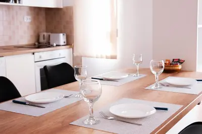 a wooden table with plates and wine glasses on it at Lux Family Apartment Vidanovic in Pirot