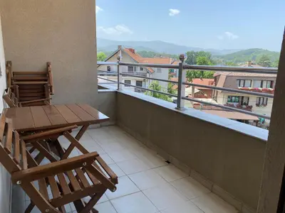 a balcony with a wooden table and chairs on a balcony at Apartman Luka in Vrnjačka Banja