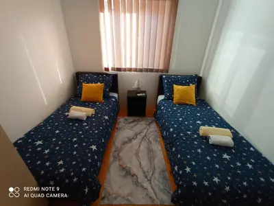 two beds in a small room with yellow pillows at Apartman Sunce in Soko Banja