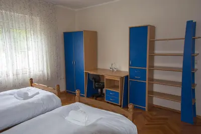 a bedroom with two beds and a desk and blue cabinets at Vila Čair in Balajnac