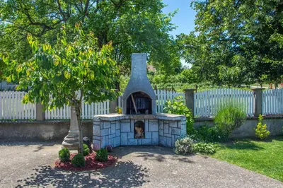 a dog sitting in a fireplace in a yard at Vila Čair in Balajnac