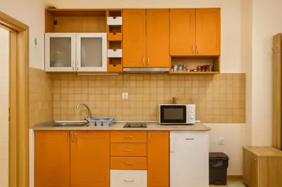 a kitchen with orange cabinets and a sink and a microwave at Cosy apartment Marina in Kopaonik