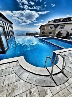 a swimming pool with blue water in front of a building at Milmari S70 Kopaonik in Kopaonik