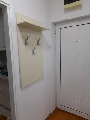 a kitchen with a white wall with a shelf and a door at Rudolf apartmani in Soko Banja