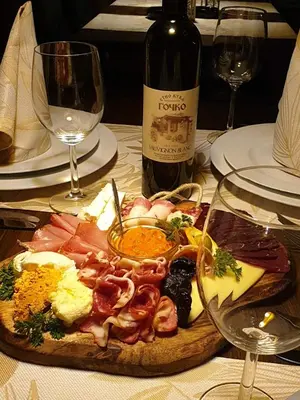 a plate of food on a table with a bottle of wine at Etno kuca sa konacistem GOCKO in Vrnjačka Banja