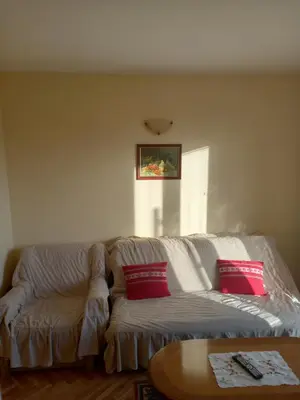 a living room with a white couch with red pillows at Apartmani Ivančica in Vrnjačka Banja