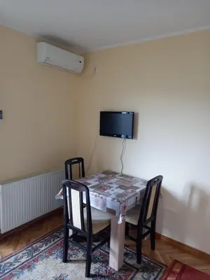 a dining room table with chairs and a tv on the wall at Apartmani Ivančica in Vrnjačka Banja