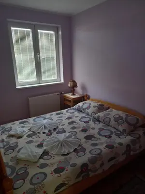 a bedroom with a bed with a floral bedspread and a window at Apartmani Ivančica in Vrnjačka Banja