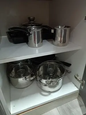 four pots and pans on a shelf in a kitchen at Stan na dan in Aleksinac