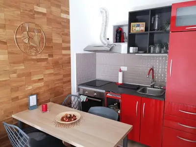 a kitchen with red cabinets and a wooden table at B3 Sneznik-Modern apartment in Vrnjačka Banja