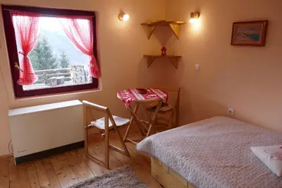 a bedroom with a bed and a table and a window at Studio za dvoje u Planinskoj kući Savić in Kopaonik