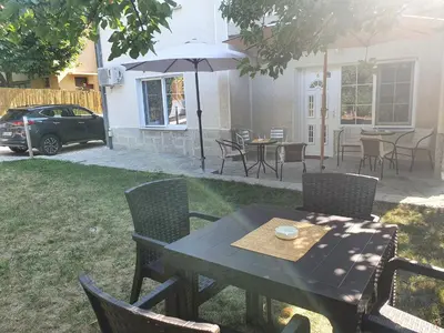 a table and chairs with an umbrella in a yard at Guest House Jasmin in Niška Banja