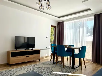 a living room with a dining room table and a television at Zlatna Kruna - Lux Apartments Kopaonik in Kopaonik
