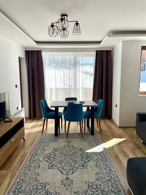 a dining room with a table and blue chairs at Zlatna Kruna - Lux Apartments Kopaonik in Kopaonik