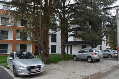 two cars parked in a parking lot in front of a building at Apartman Rajak in Vrnjačka Banja