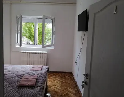 a small bedroom with a bed and a window at Apartman Nana Jagodina in Jagodina