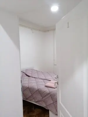 a small bedroom with a bed in a white room at Apartman Nana Jagodina in Jagodina