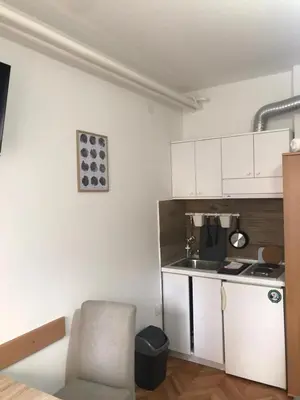 a kitchen with white cabinets and a chair in a room at Smeštaj Filipović in Soko Banja