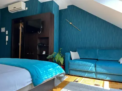 a blue bedroom with a bed and a couch at Pleasure Čair apartments in Niš