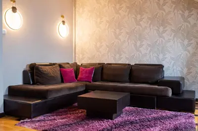 a living room with a brown couch with pink pillows at Pleasure Čair apartments in Niš