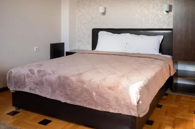 a bedroom with a large bed with a wooden floor at Pleasure Čair apartments in Niš