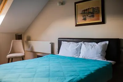 a bedroom with a blue bed and a chair at Pleasure Čair apartments in Niš