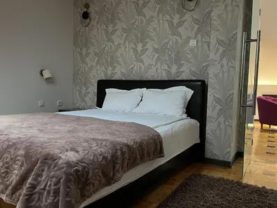 a bed with white pillows and a gray wall at Pleasure Čair apartments in Niš