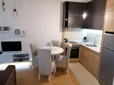 a kitchen with a white table and chairs in a kitchen at Emili Apartman in Jagodina